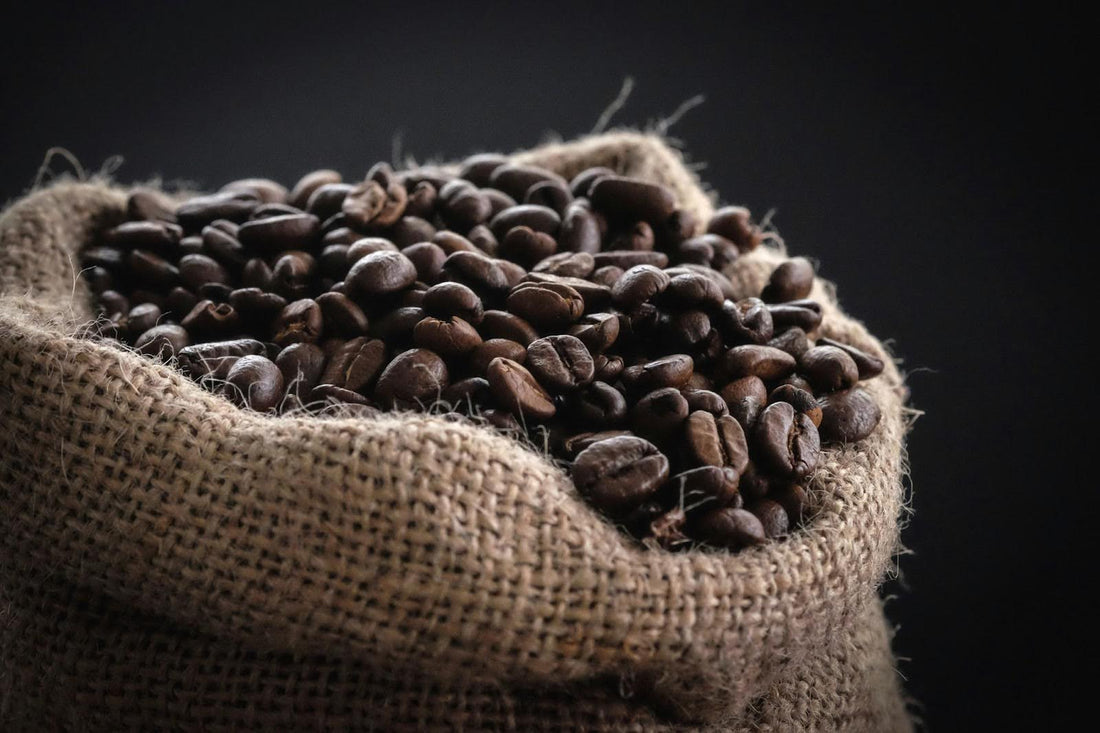 A burlap bag overflowing with organic coffee beans