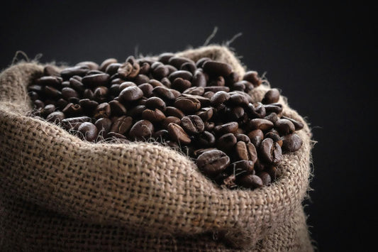 A burlap bag overflowing with organic coffee beans
