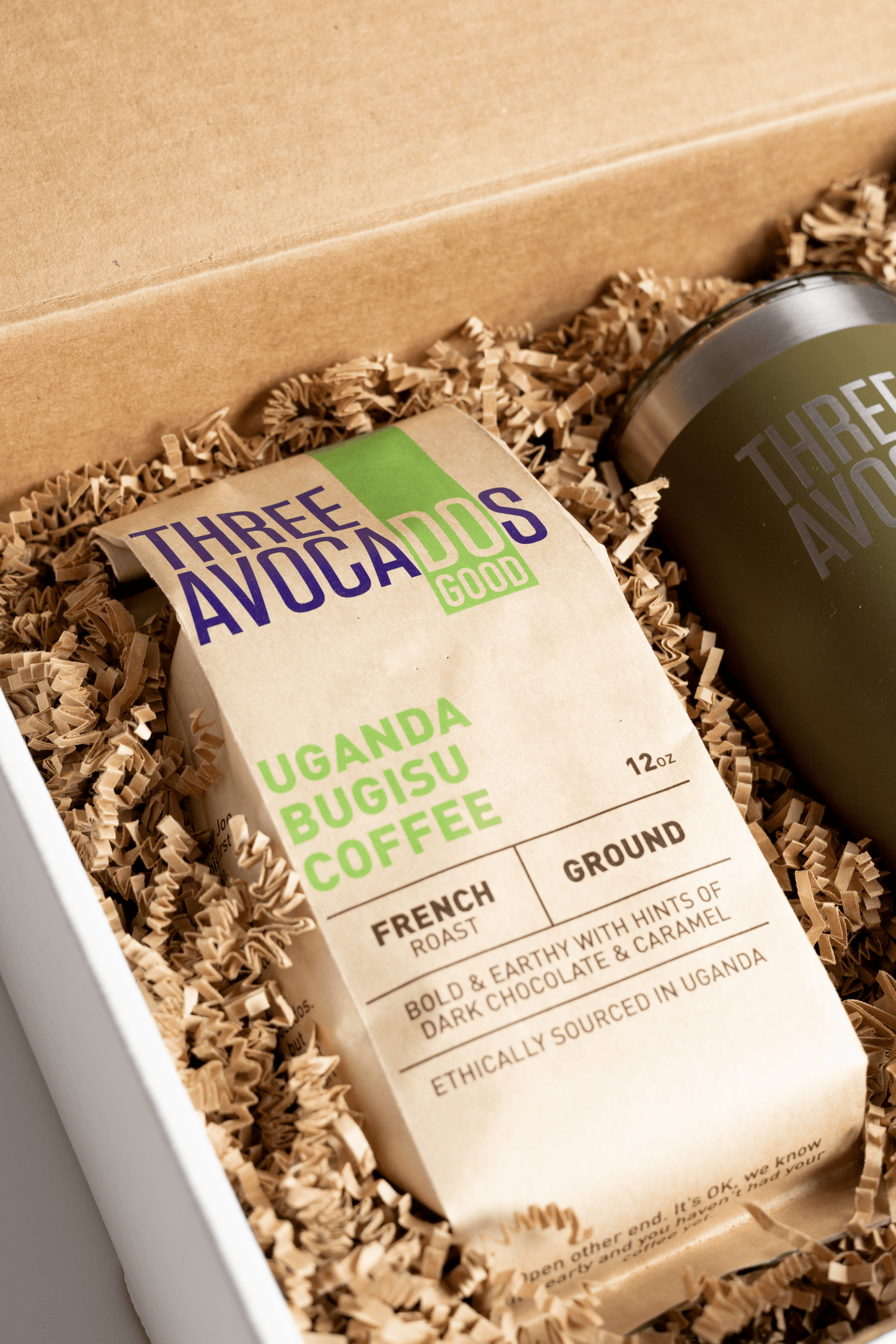 A bag of coffee and tumbler in a box, focused on the bag of Ugandan coffee
