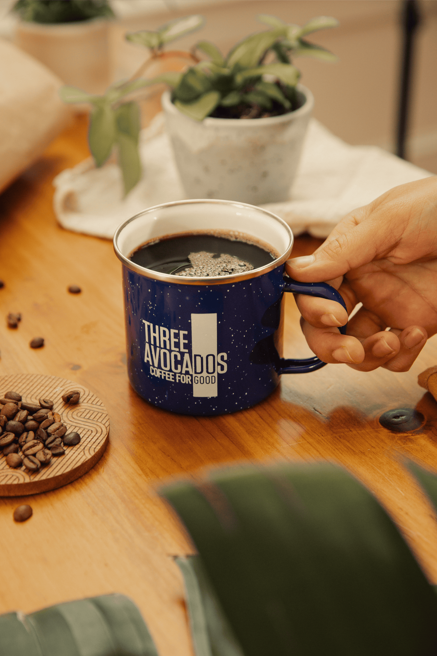 A hand holding a blue enamel mug of coffee