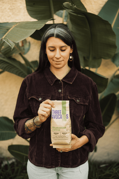 A woman holding a bag of Nicaraguan coffee in front of a plant