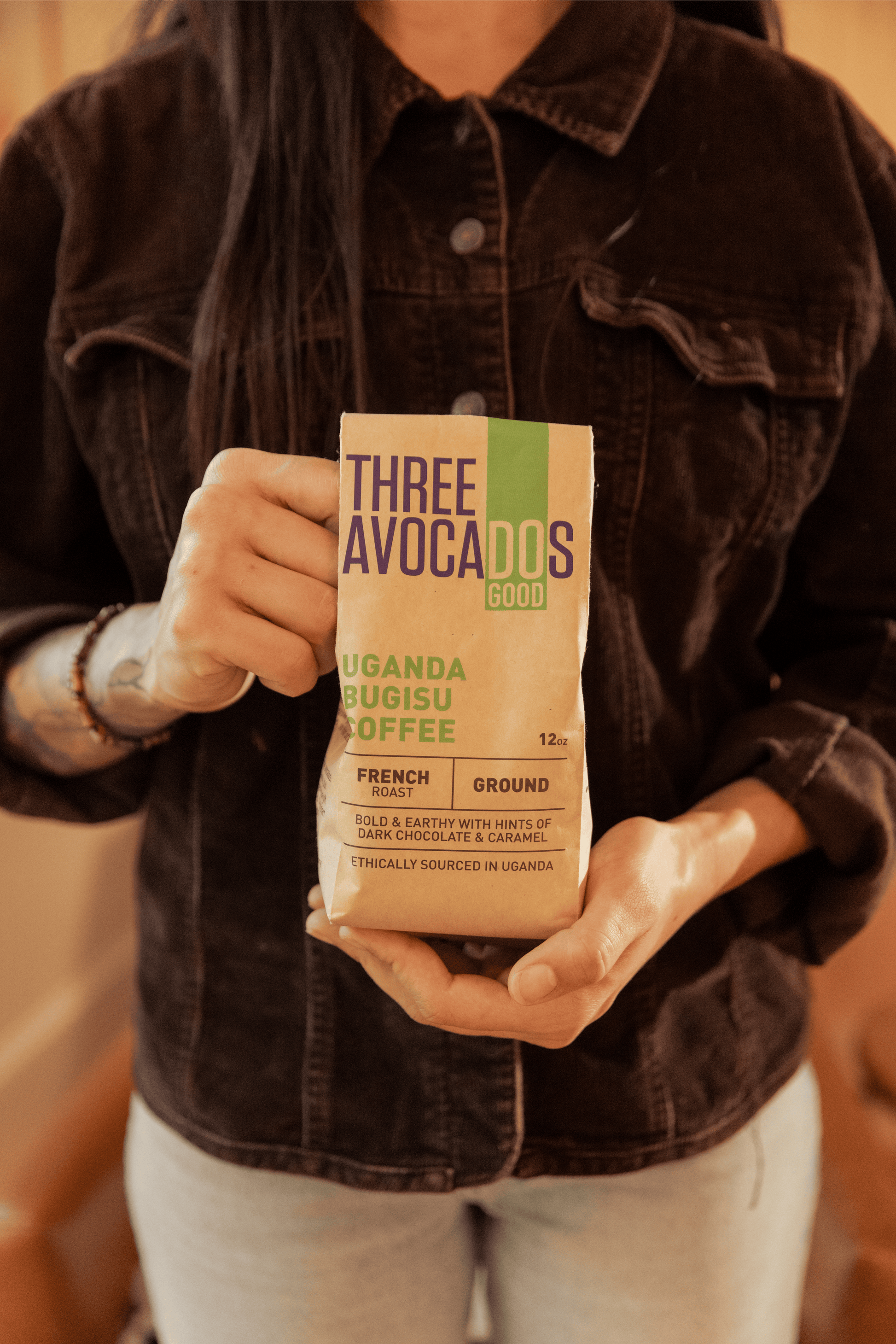 A woman holds a bag of Ugandan coffee